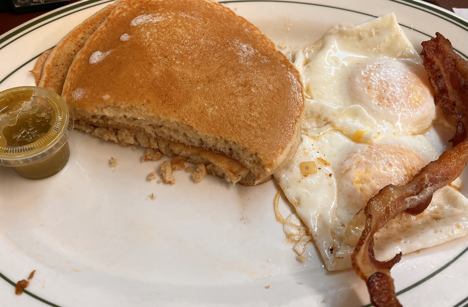 Pancake breakfast plate with fried eggs and crispy bacon