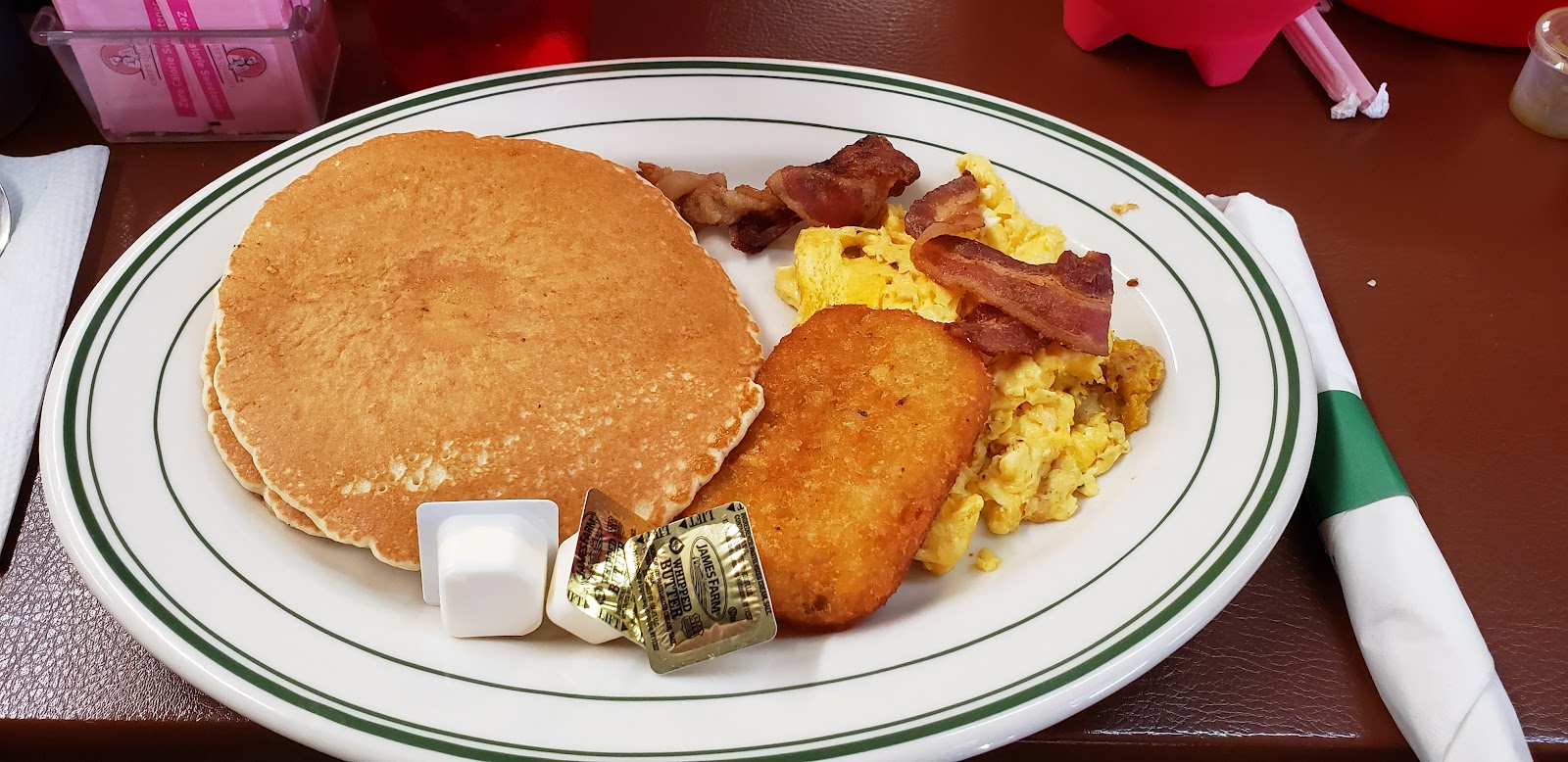 Pancakes with butter and syrup, served with hash browns, eggs, and bacon