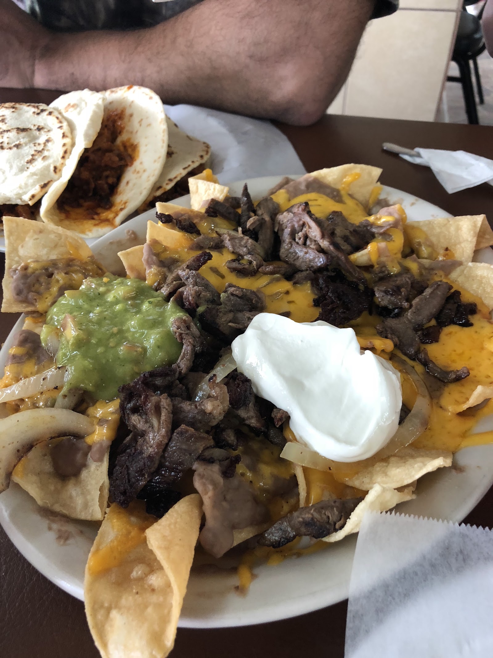Loaded nachos with carne asada, melted cheese, guacamole, and sour cream
